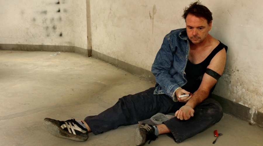 Man laying on ground injecting a needle - How Meth Addiction Influences Depression