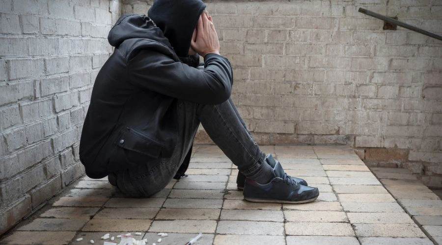 Man sitting outside near a stairwell holding his hands on his face displaying Long-Term Substance Use Disorder Cause Mental Health Disorder