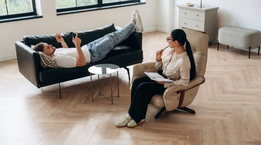 Patient laying on sofa with counselor sitting nearby in a chair displaying Residential treatment program for intensive help