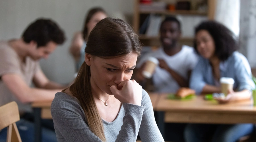 Image of a young woman looks distressed sitting in front of four peers.