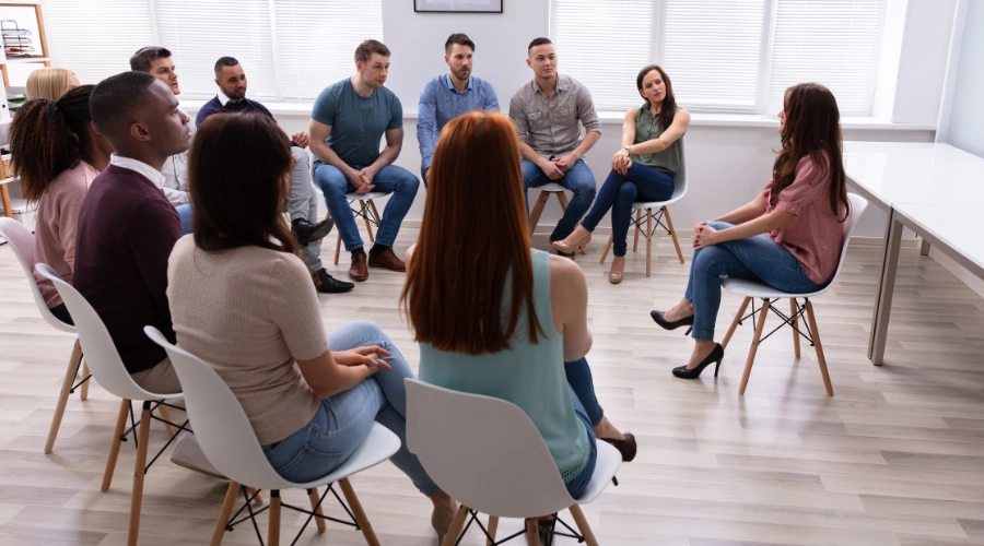 AA meeting participant sitting in a circle with a group chairperson