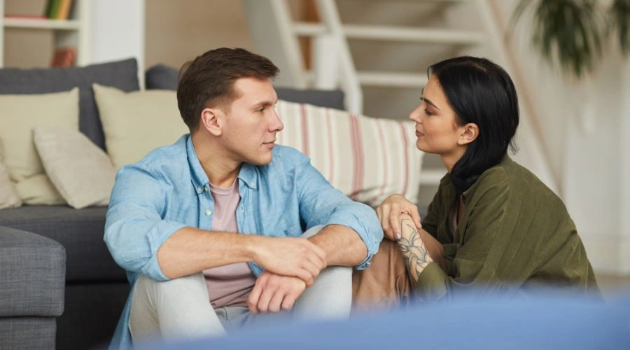 Image of a Couple sitting in front of a sofa, staring into each others eyes