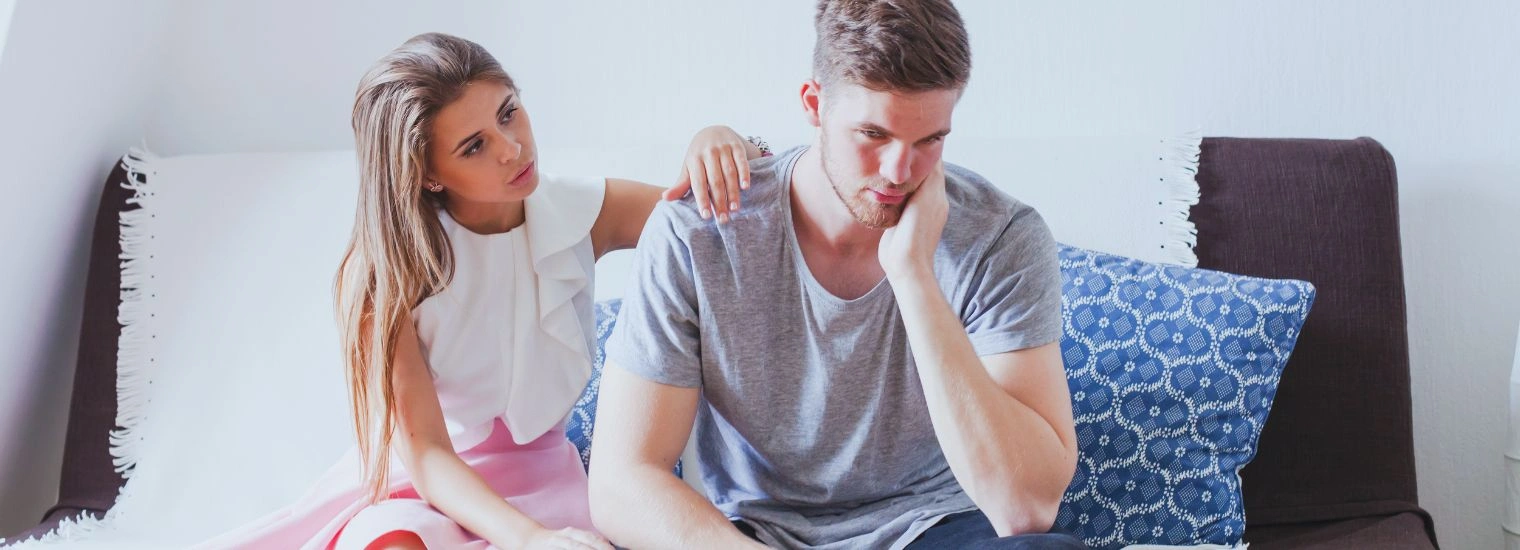 Image of a female sitting on a sofa, consoling her brother - How to Help an Alcoholic Sibling - Icarus Nevada