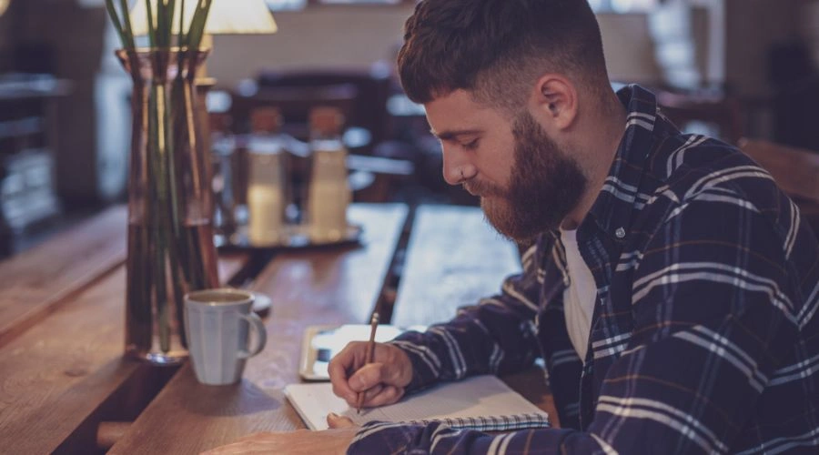 Man writing an amends letter in a journal