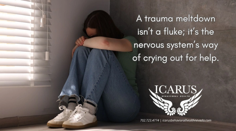 Image of a female sitting on the floor next to a wall with her face and arms on her knees - What is a trauma meltdown - Icarus Nevada