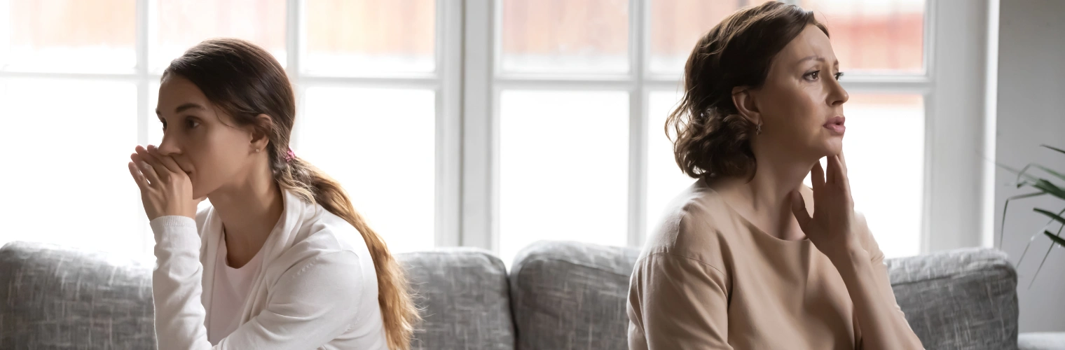 Image of a mother and daughter sitting on a sofa apart and looking away from each other - How to Break Generational Trauma - Icarus Behavioral Health