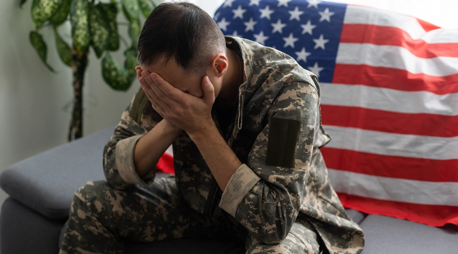 Image of a sad veteran sitting alone on a sofa, reflecting on past war trauma