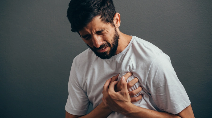 Image of a man clutching his chest with visible distress, symbolizing the intense cardiovascular and neurological dangers of fish scale cocaine use