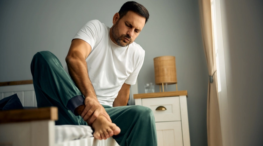 Image of a man holding his legs in pain, showing nerve damage and discomfort from alcoholic neuropathy