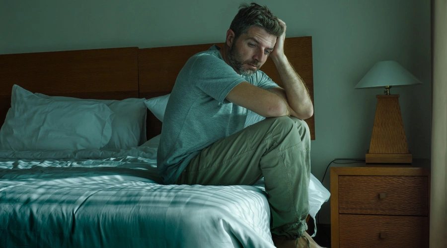 Image of a sad man sitting on a bed, reflecting the emotional distress and early signs of meth use