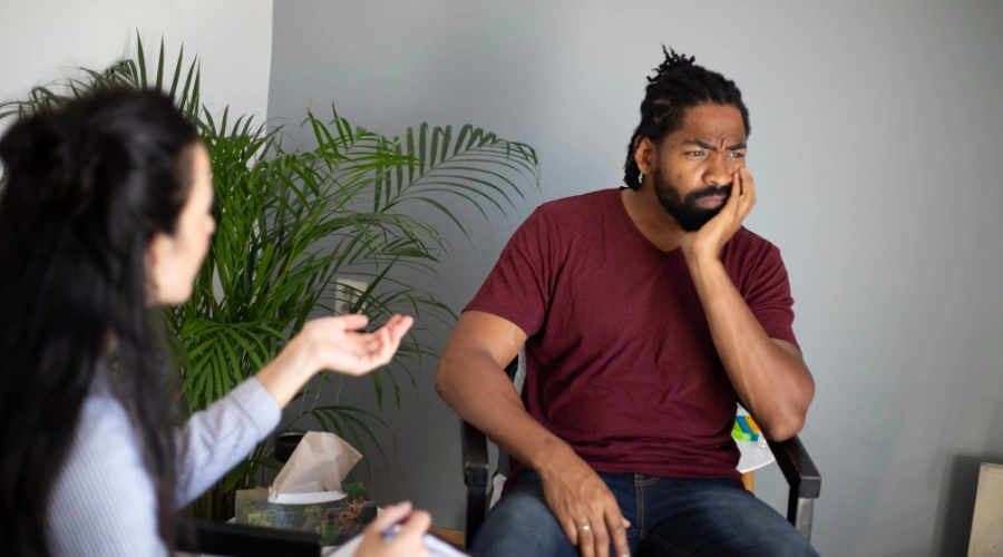 Image of a man looking unhappy and meeting with a therapist at a depression retreat