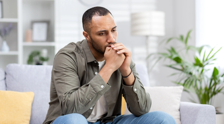 Image of a man looking pensive, sitting alone in thought, as he begins his recovery process