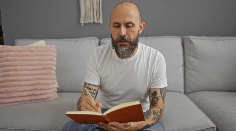 Image of a man writing in his notebook and listing the consequences of his alcohol addiction