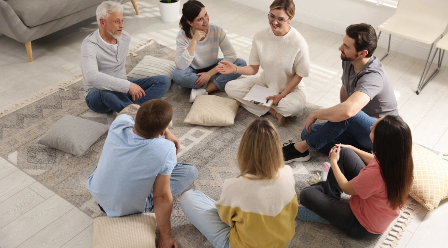 Image of men and women sitting on the floor, guided by a counselor in a holistic depression treatment session